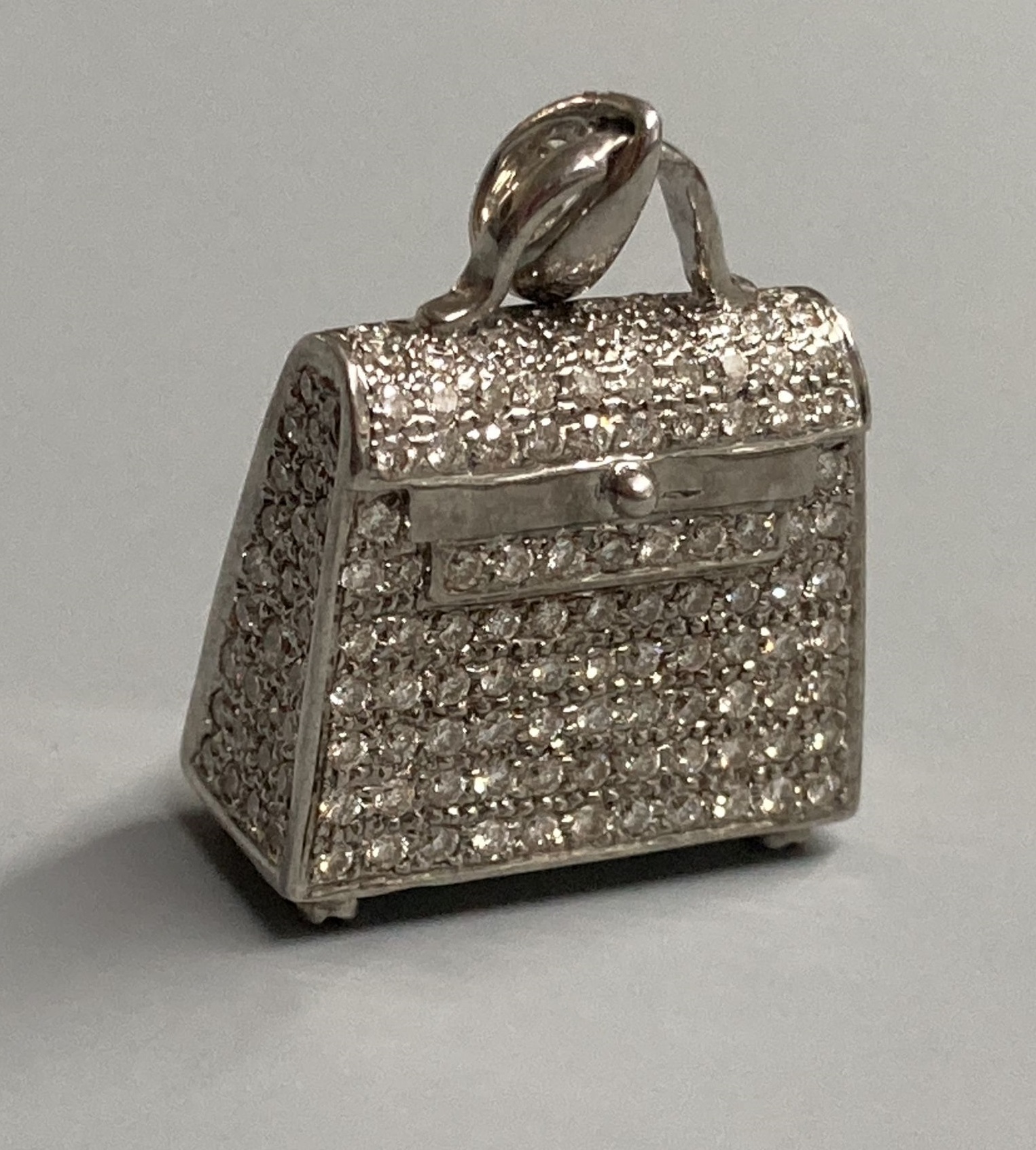 A modern 18k 750 white metal and diamond encrusted handbag charm, with diamond set bale and four diamond set feet, 22mm, gross 9.7 grams